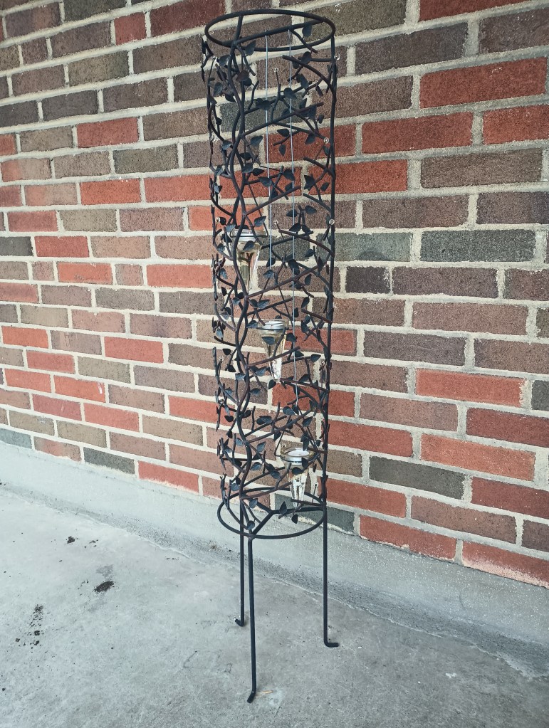 A large votive candle holder for three cascading candles within a botanical themed frame